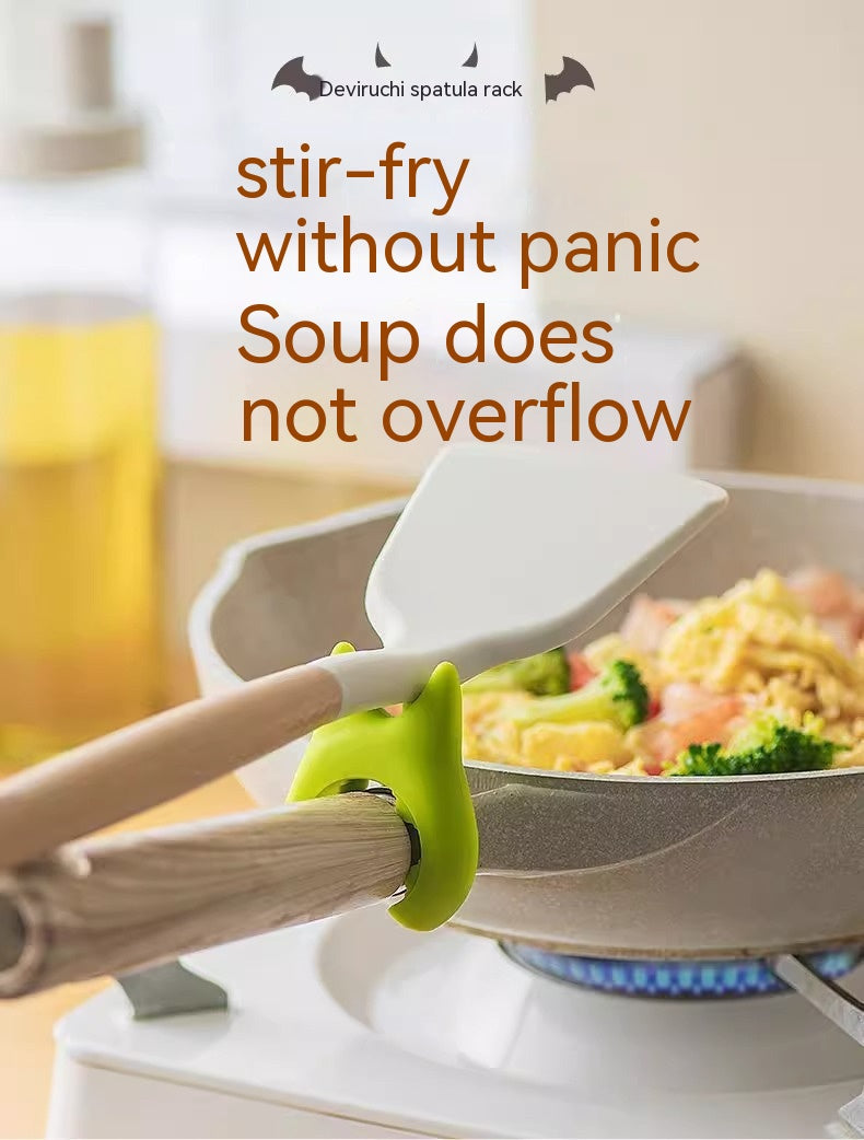 Pot clip holding a spatula on a pan over a stove