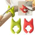 Green silicone pot clip holding a spoon on a pan handle
