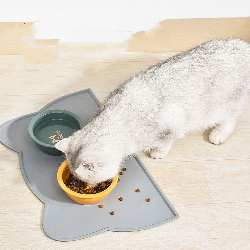 Cat eating from a bowl on a grey silicone mat