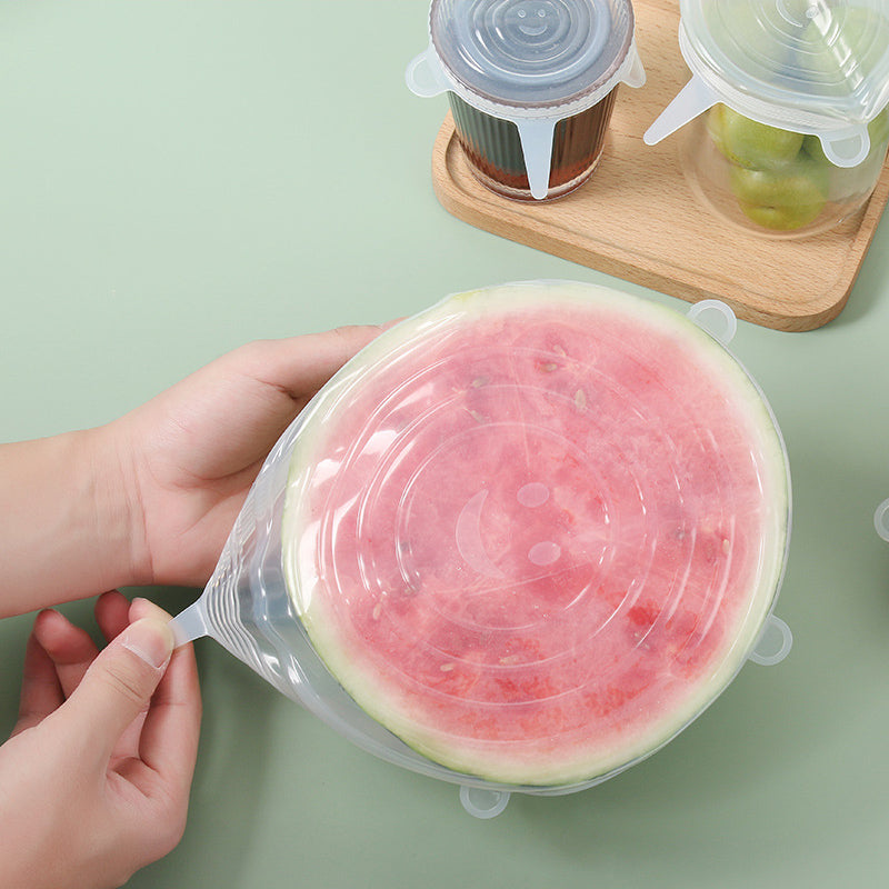 Hands stretching a silicone lid over half a watermelon